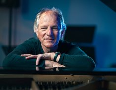 Andreas Herkenhöhner Portrait Andreas Herkenhöhner lehnt auf dem Klavier