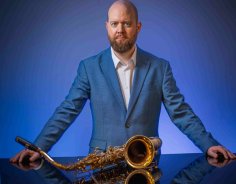 Michel Janssen Portrait von Michel Janssen vor einem Klavier auf dem ein Saxophon liegt